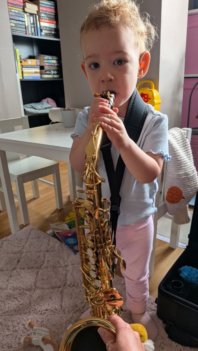 A toddler trying out a saxophone